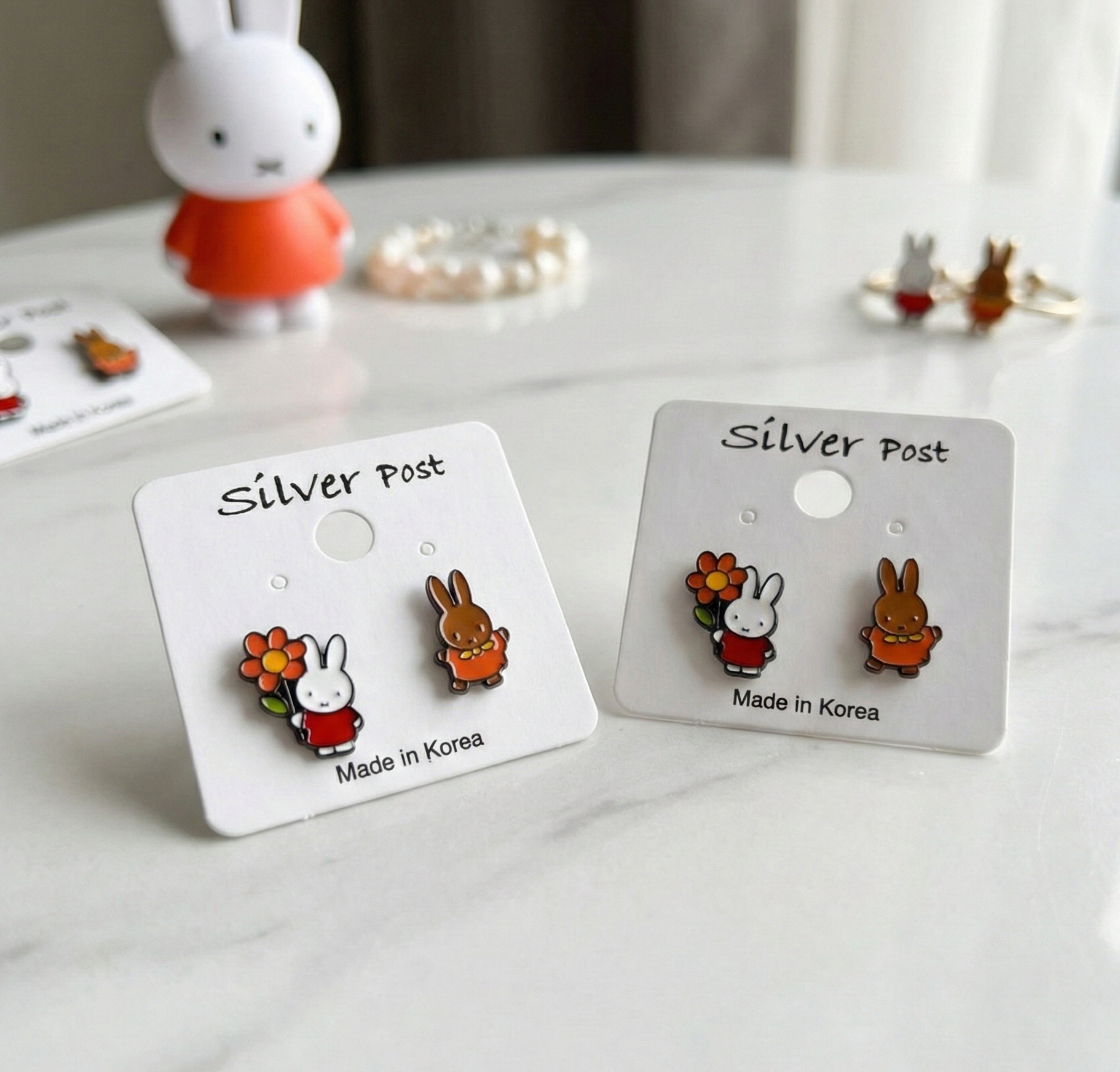 Two pairs of Miffy Melanie earrings on white cards showing Made in Korea silver post marking, friendship gift set idea