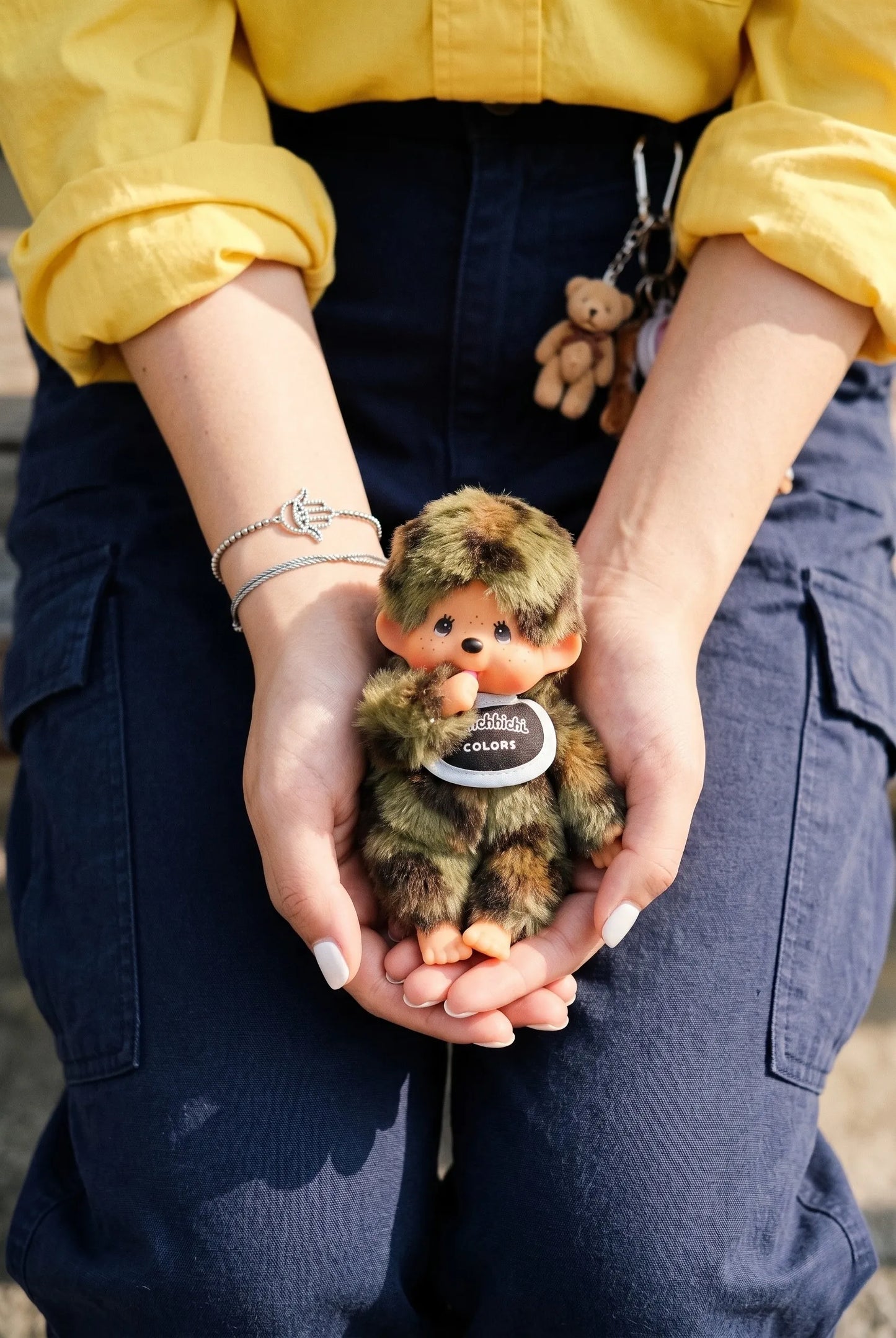 Lifestyle hand-hold shot of camo plush doll keychain 8ttitto8, gift-ready with original hang tag, Y2K plush charm aesthetic.