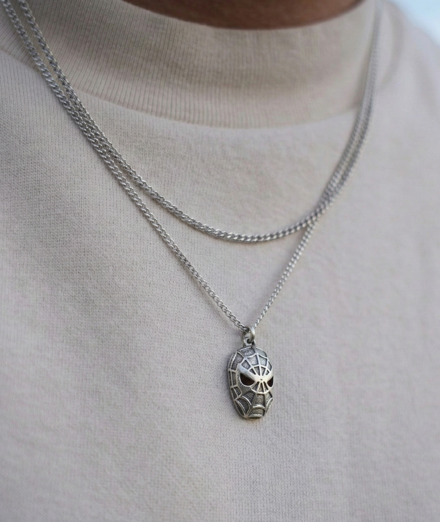 Close up of a man wearing a unisex vintage silver character pendant on a long chain