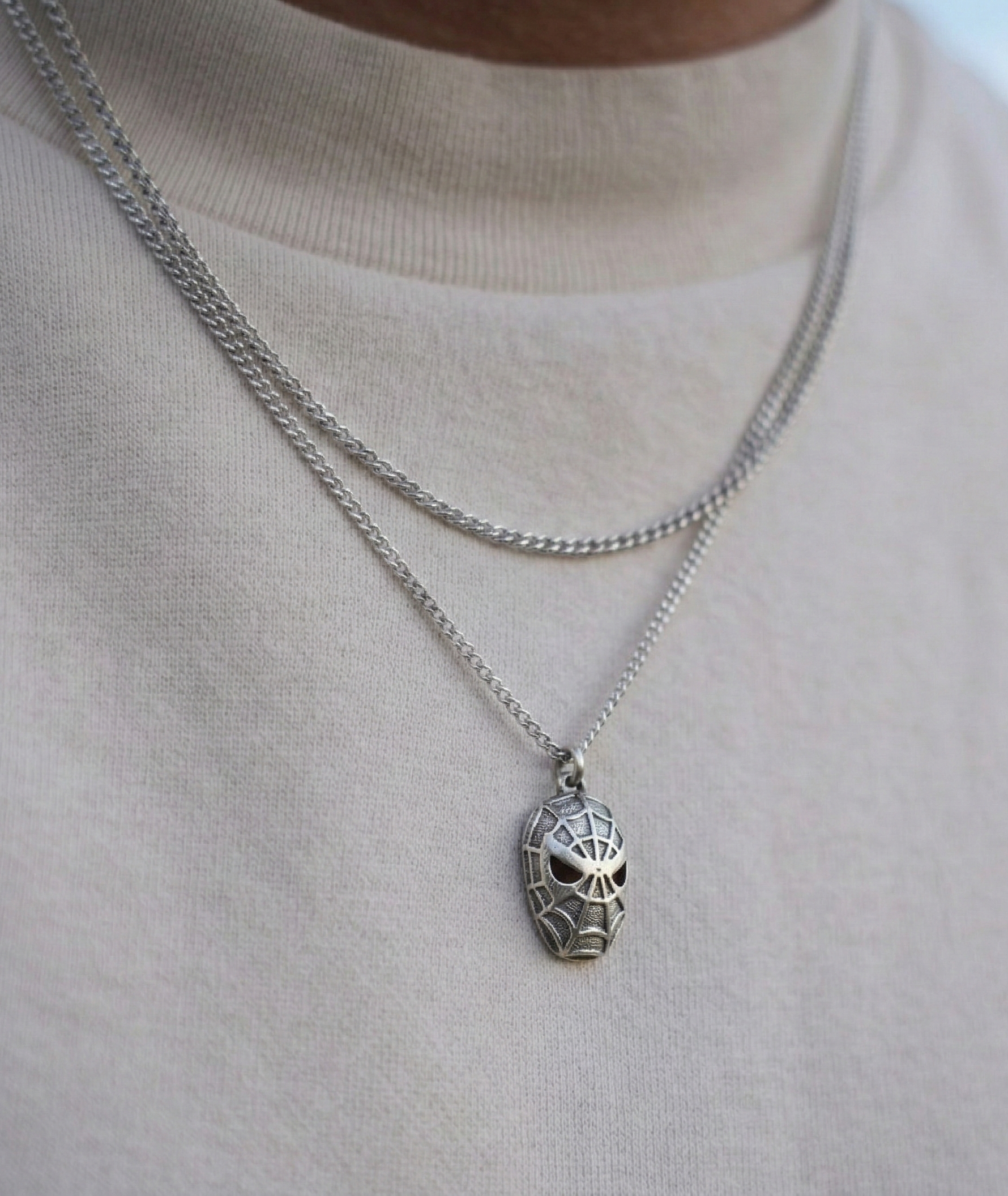Close up of a man wearing a unisex vintage silver character pendant on a long chain