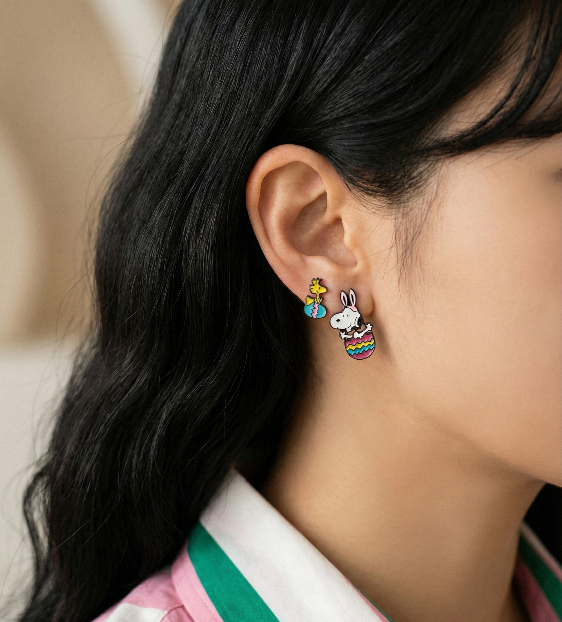 Side profile of woman wearing Snoopy Easter earrings showing drop length and asymmetrical style