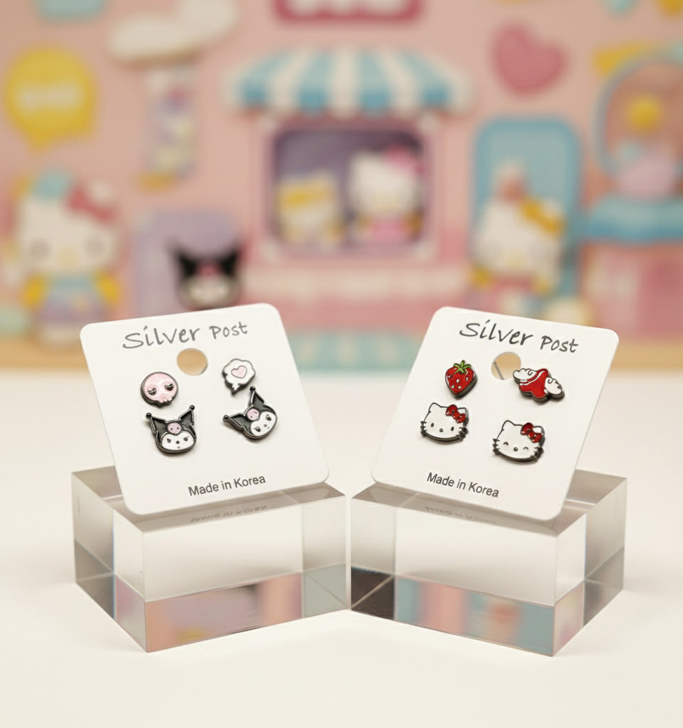 Character earring sets on white cards displayed on acrylic stands with pastel Sanrio background, Kuromi and Hello Kitty enamel studs, 925 silver posts, Made in Korea label, kawaii jewelry collection