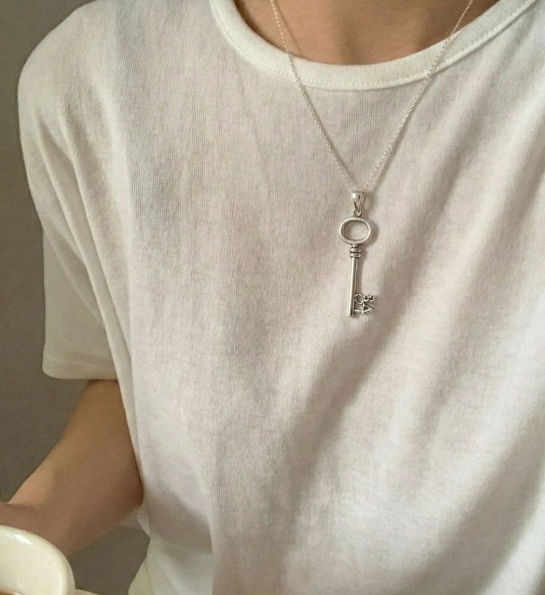Lifestyle shot of the LOVE key necklace worn casually, showing the length on the chest.