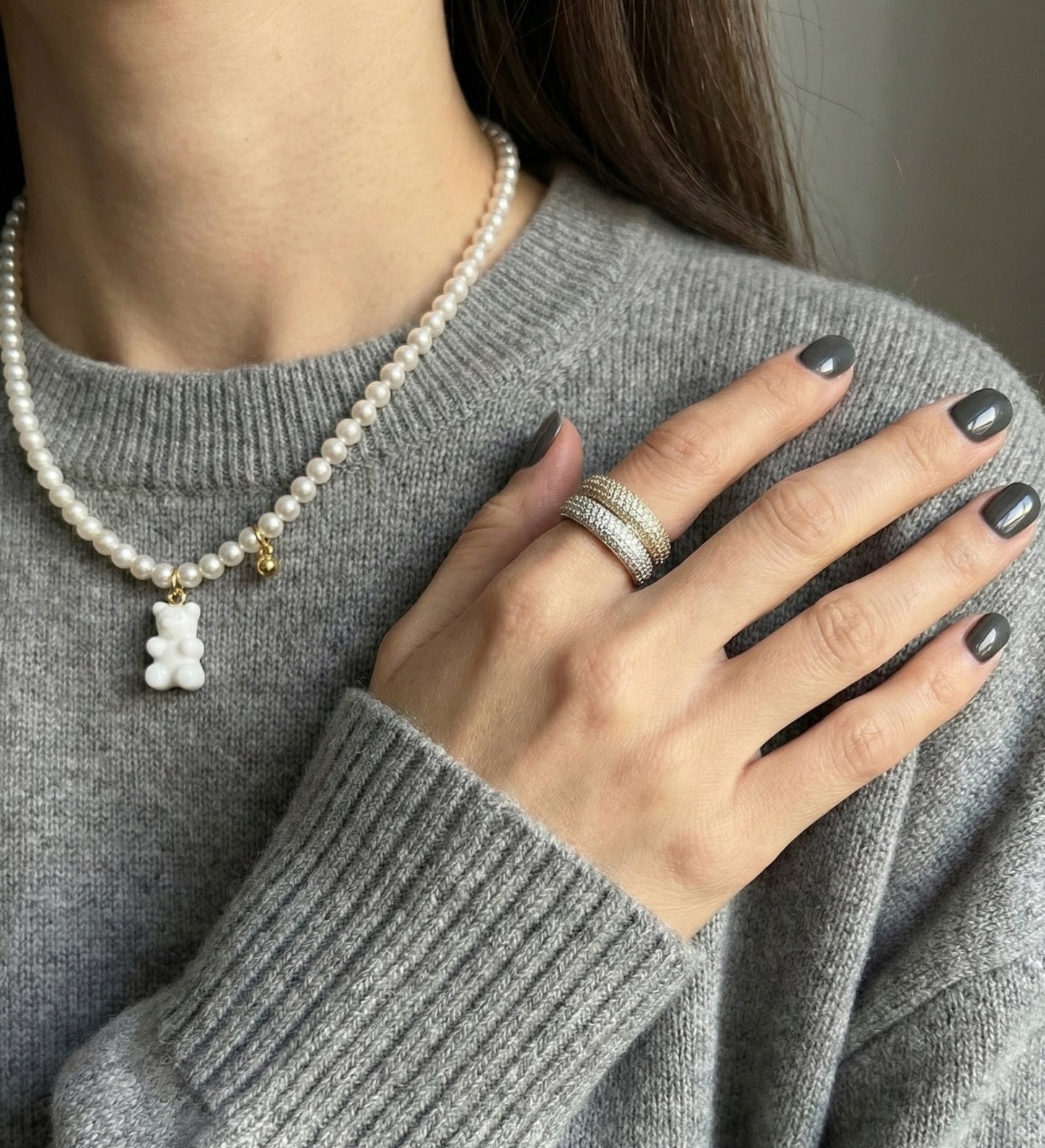 Gray sweater outfit with white pearl gummy bear necklace and stacked rings