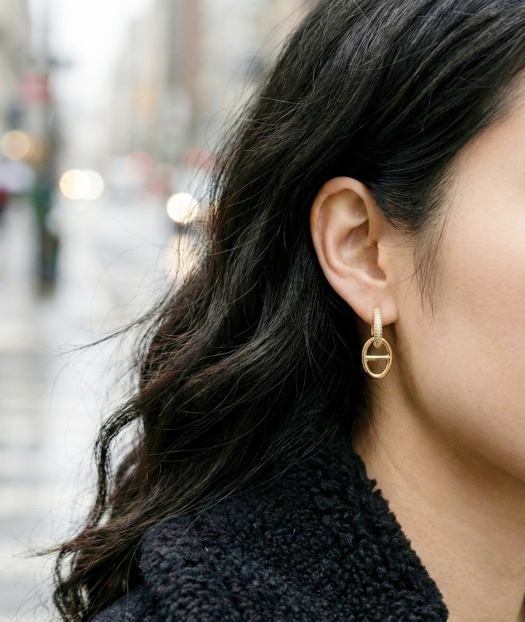 Outdoor lifestyle shot of gold anchor link huggie earrings