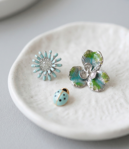 Fresh Mint floral and ladybug 3-piece earring set elegantly displayed on a white textured ceramic small plate.