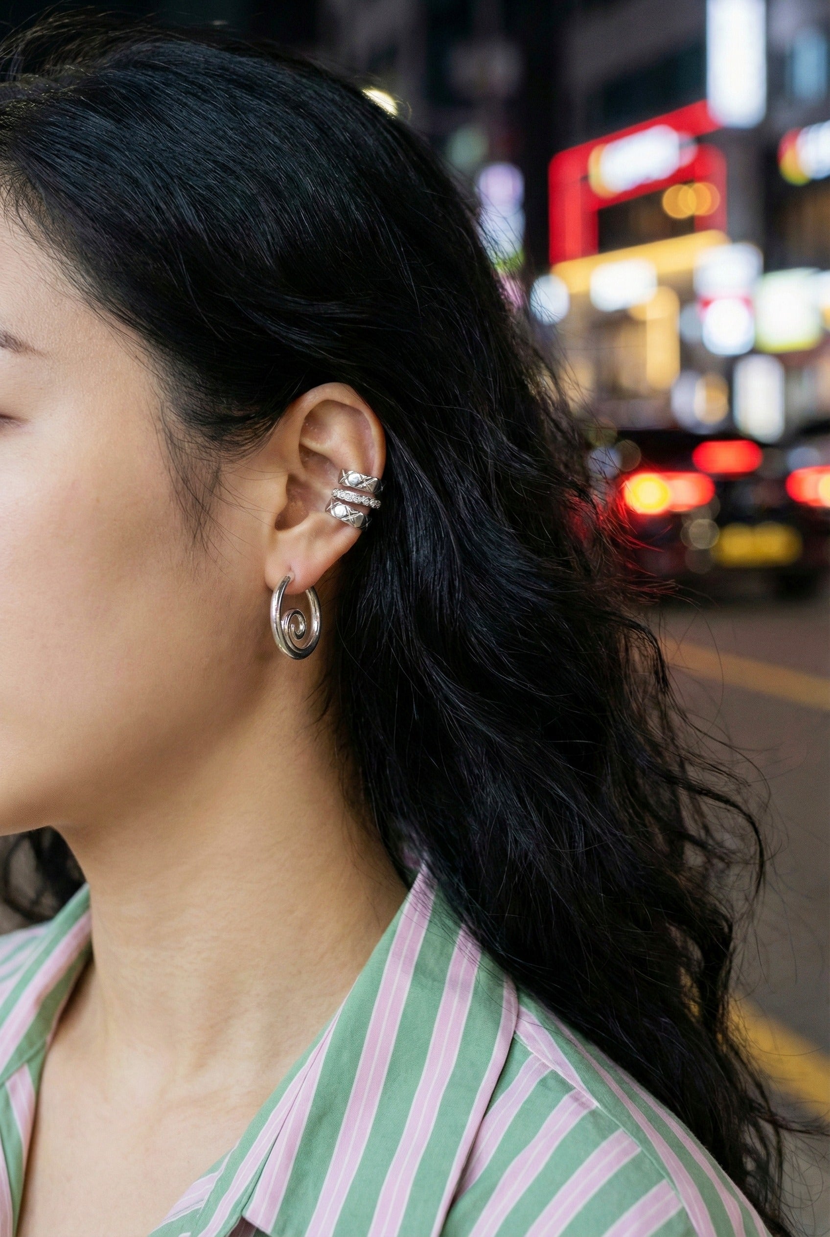 Silver spiral earrings stacked with pearl ear cuffs and multiple piercings