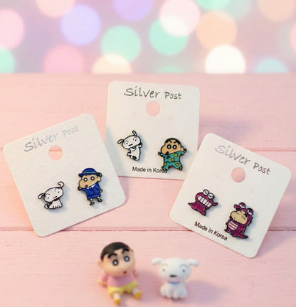 hree pairs of Shin-chan earrings displayed on white cards with cute character figurines in soft pink background