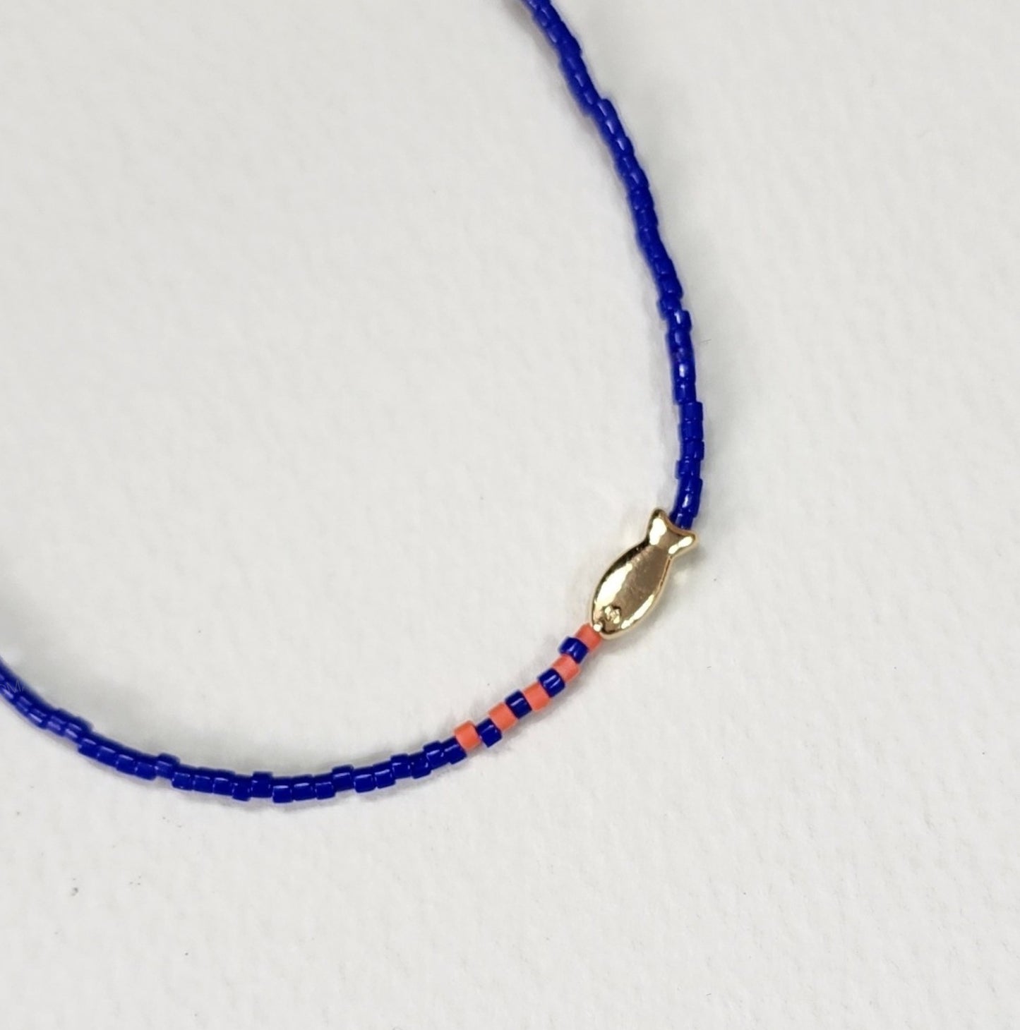 Ocean blue seed bead fish necklace with gold charm and pink accent beads close-up detail