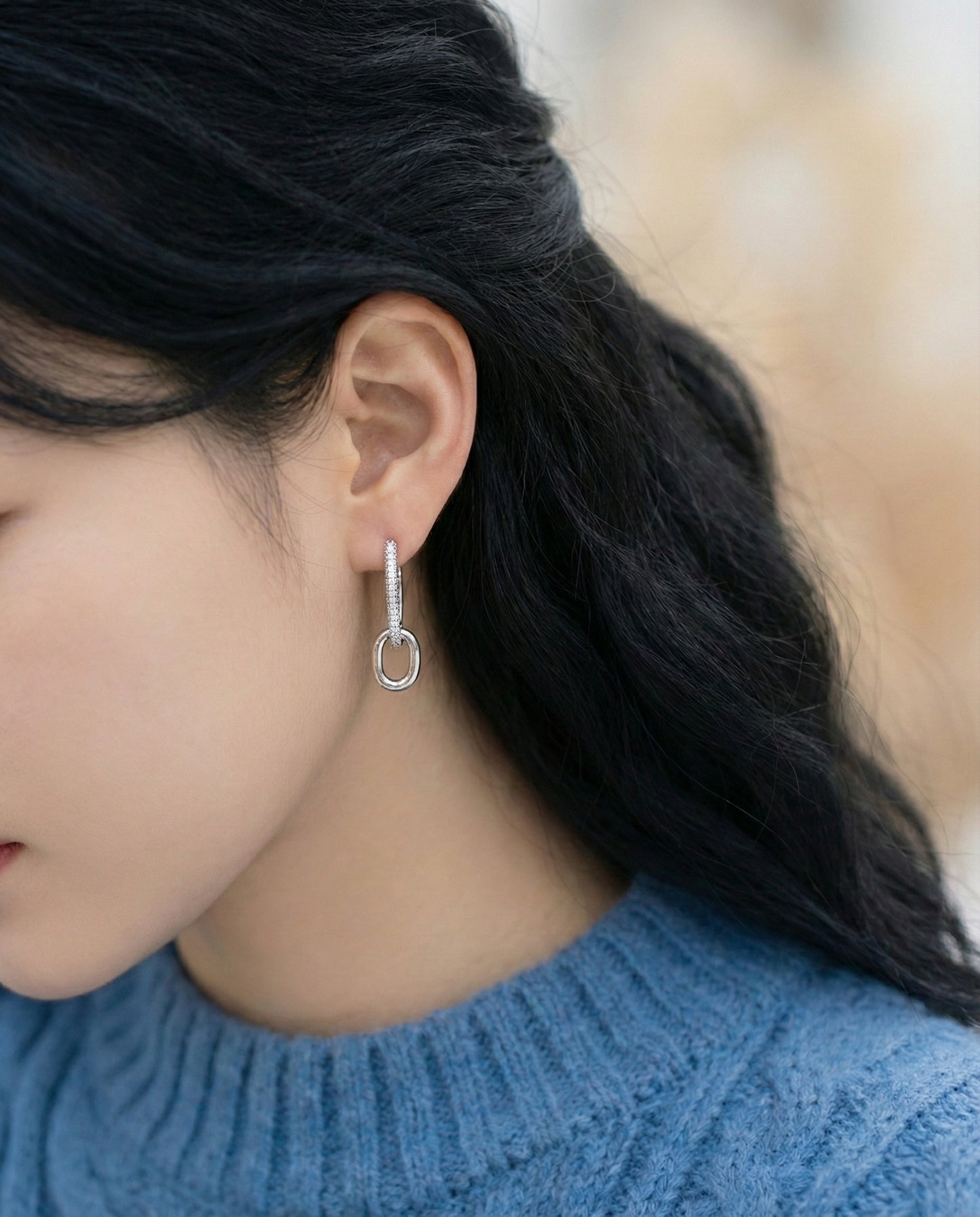 Woman wearing silver oval link drop earrings, top pave style, blue knit sweater