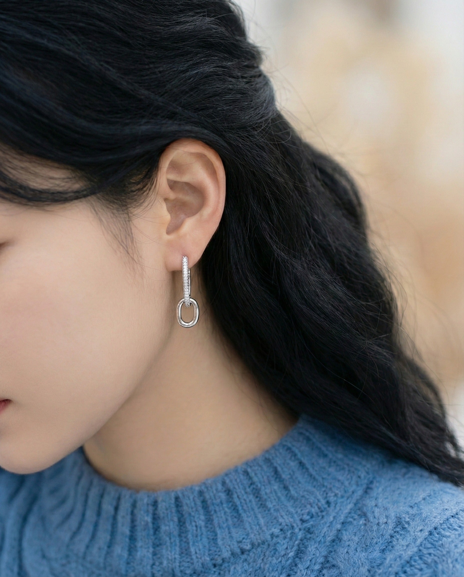 Woman wearing silver oval link drop earrings, top pave style, blue knit sweater