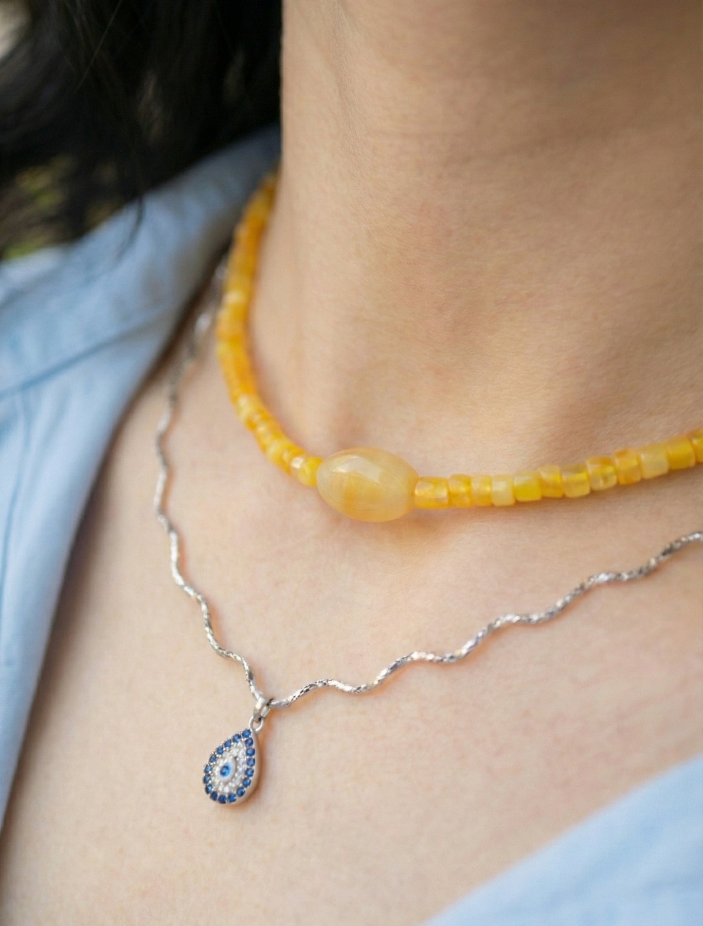 Woman wearing yellow jade choker in natural sunlight with layered silver chains