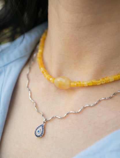 Woman wearing yellow jade choker in natural sunlight with layered silver chains