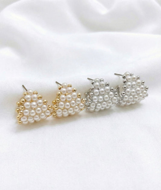 Comparison of gold and silver pearl heart hoop earrings on white fabric