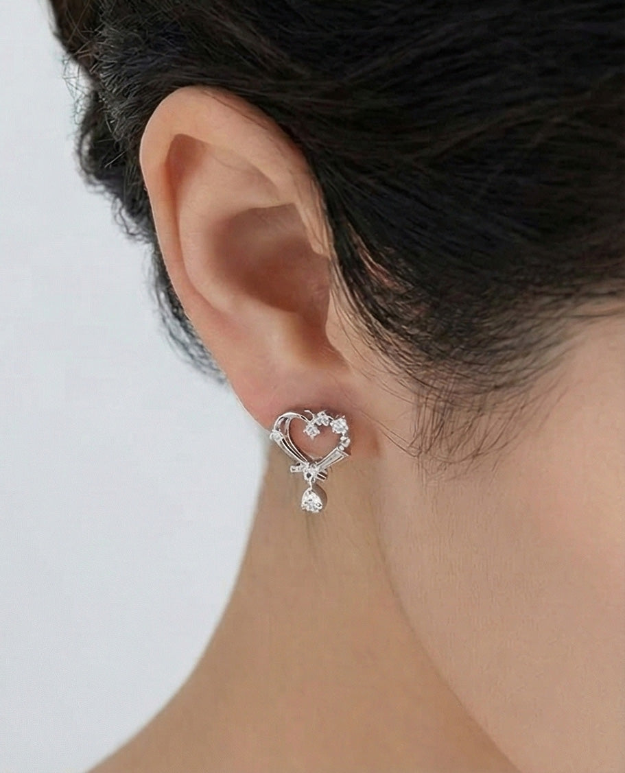 Woman wearing silver heart CZ drop earrings with baguette crystal detail, side view showing lightweight romantic design, 925 sterling silver posts Korean made