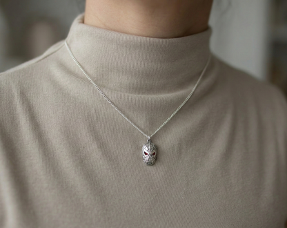 Woman modeling a chunky silver spider mask necklace over a beige turtleneck