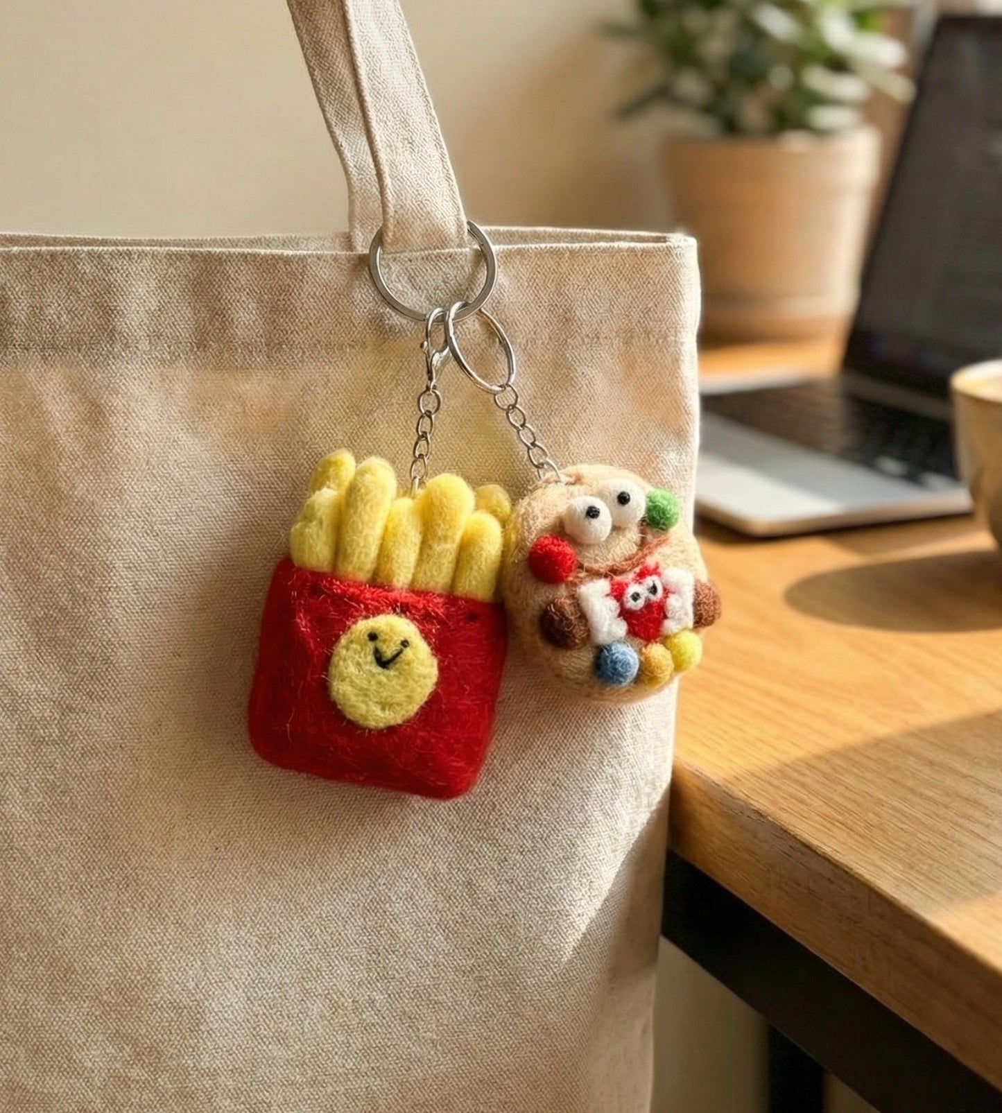 Happy fries and cookie monster wool felt keychains hanging on beige tote bag handle, aesthetic bag styling