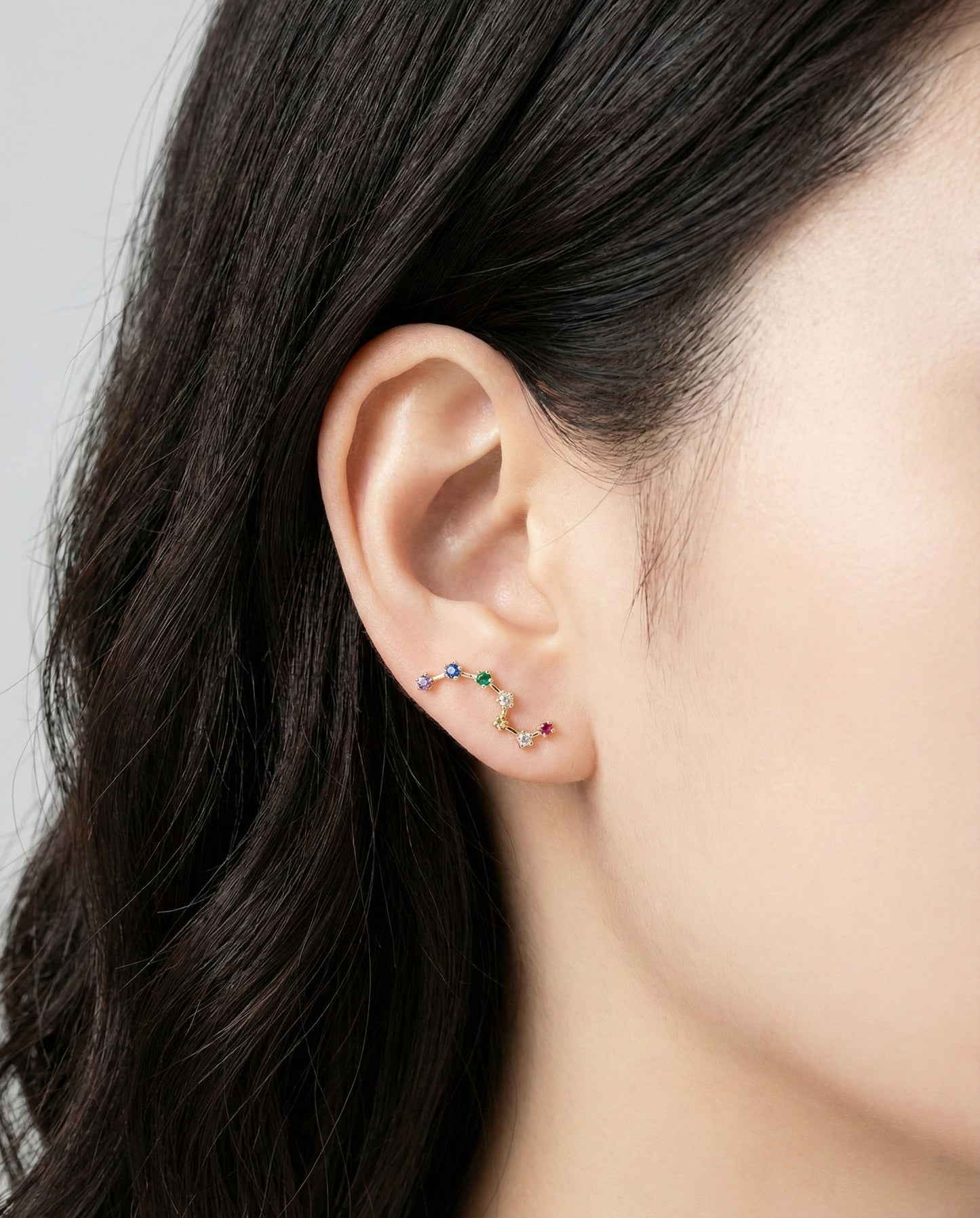 Model wearing rainbow Big Dipper ear climber on earlobe showing constellation design