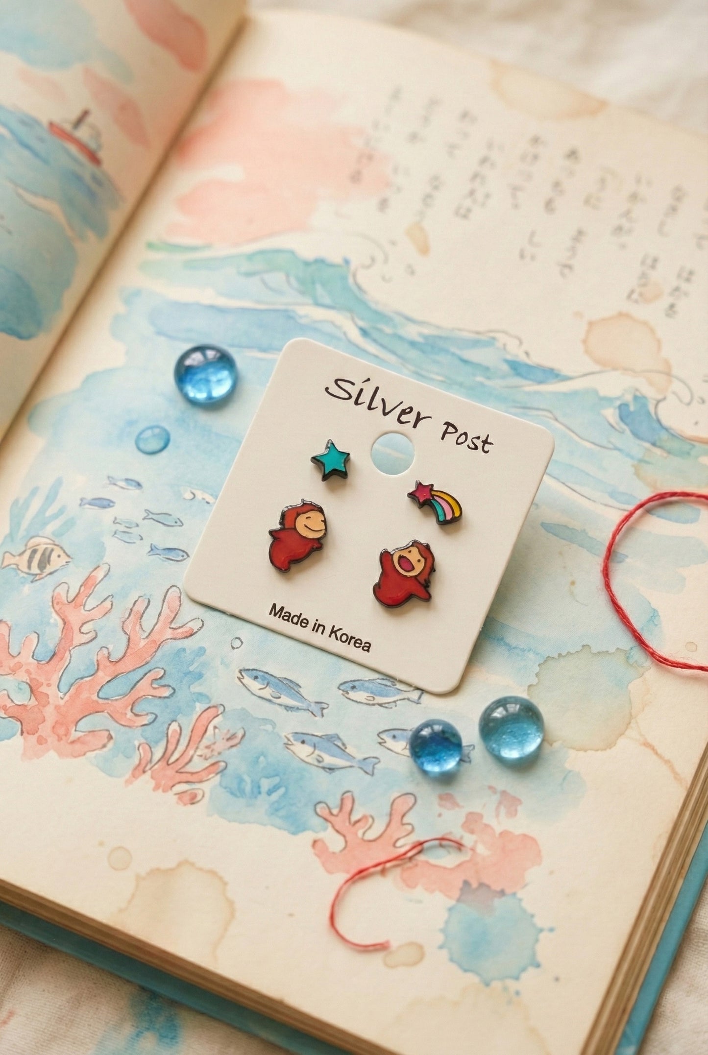 Ponyo earring set displayed on vintage book with ocean illustration