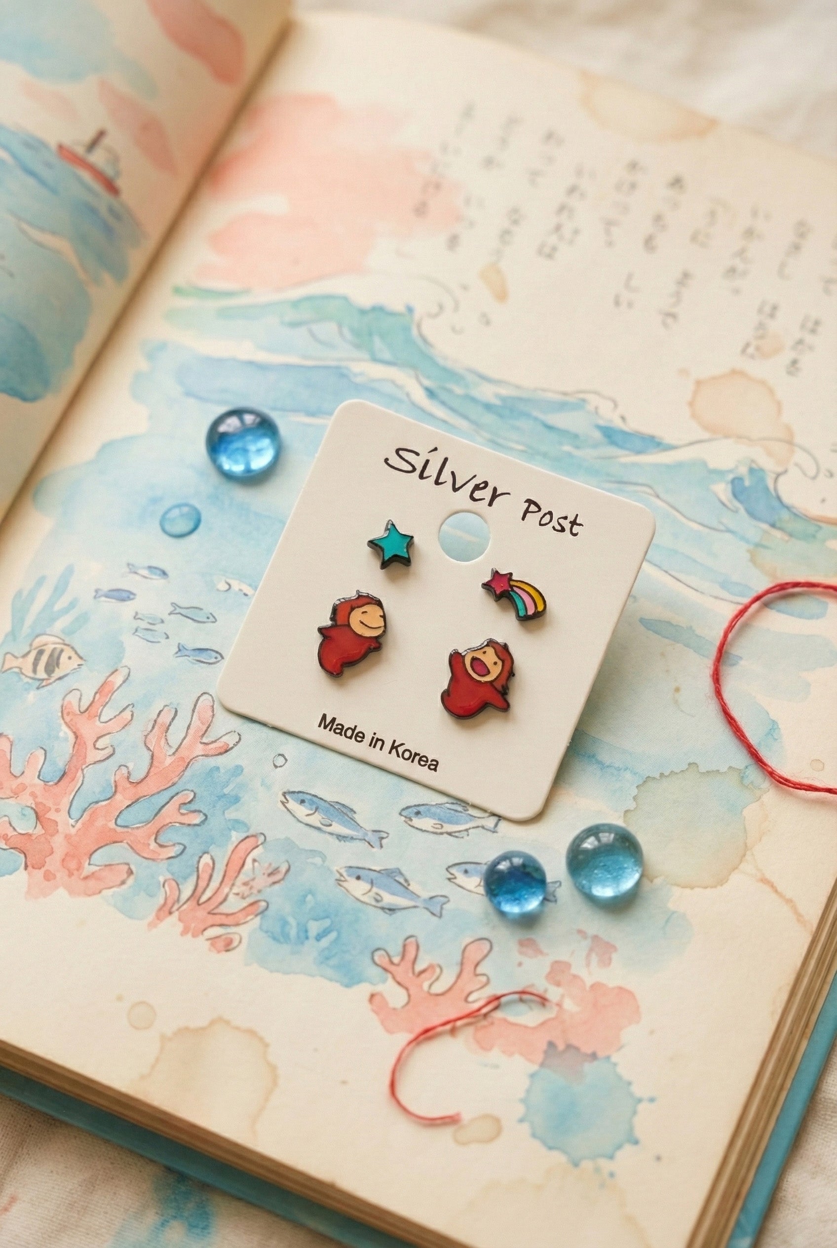 Ponyo earring set displayed on vintage book with ocean illustration