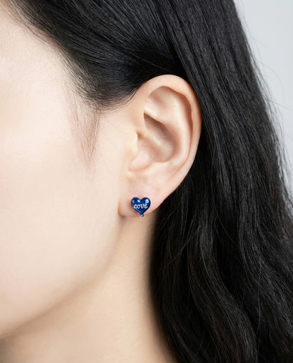 Side profile of woman wearing royal blue heart balloon stud earring