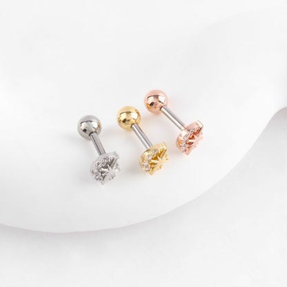 Three titanium barbell piercings with moon and star motif in silver, gold, and rose gold