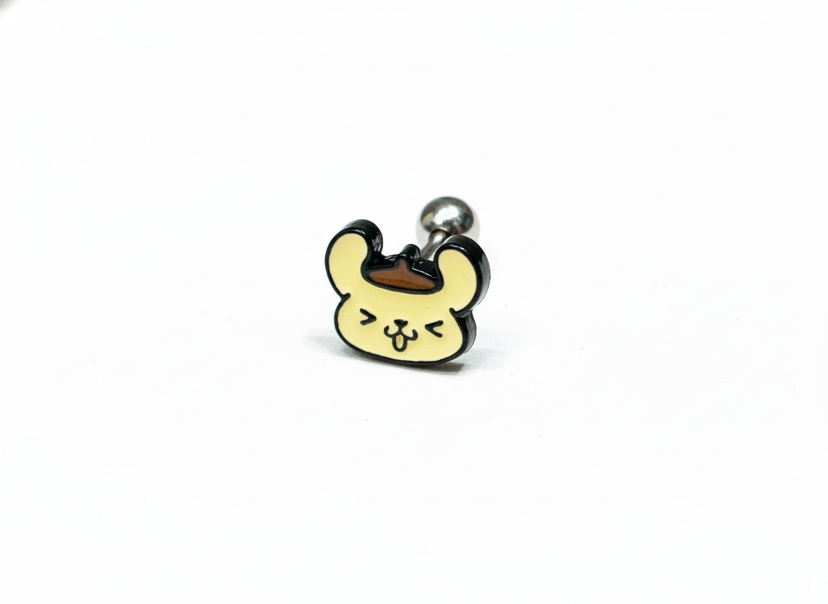 A close-up of a barbell piercing with a smiling Pompompurin face design, featuring a beret and playful expression on a white background.