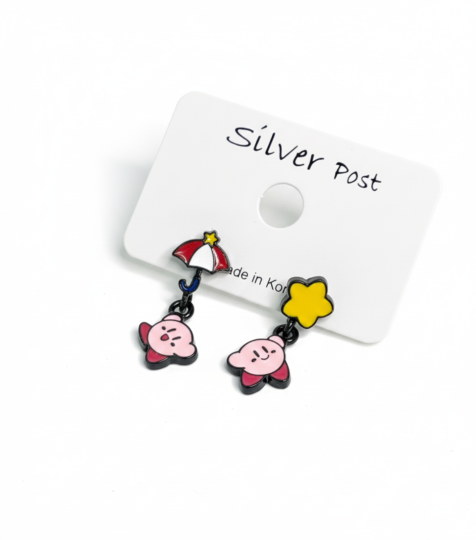Close-up of mismatched Kirby earrings on a display card — one with red umbrella and flying Kirby, the other with a yellow star and smiling Kirby.