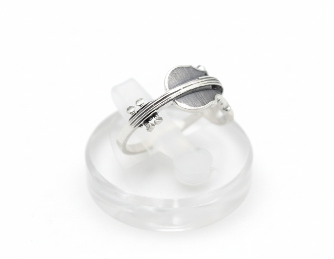 Silver violin ring displayed on clear stand, detailed strings visible.