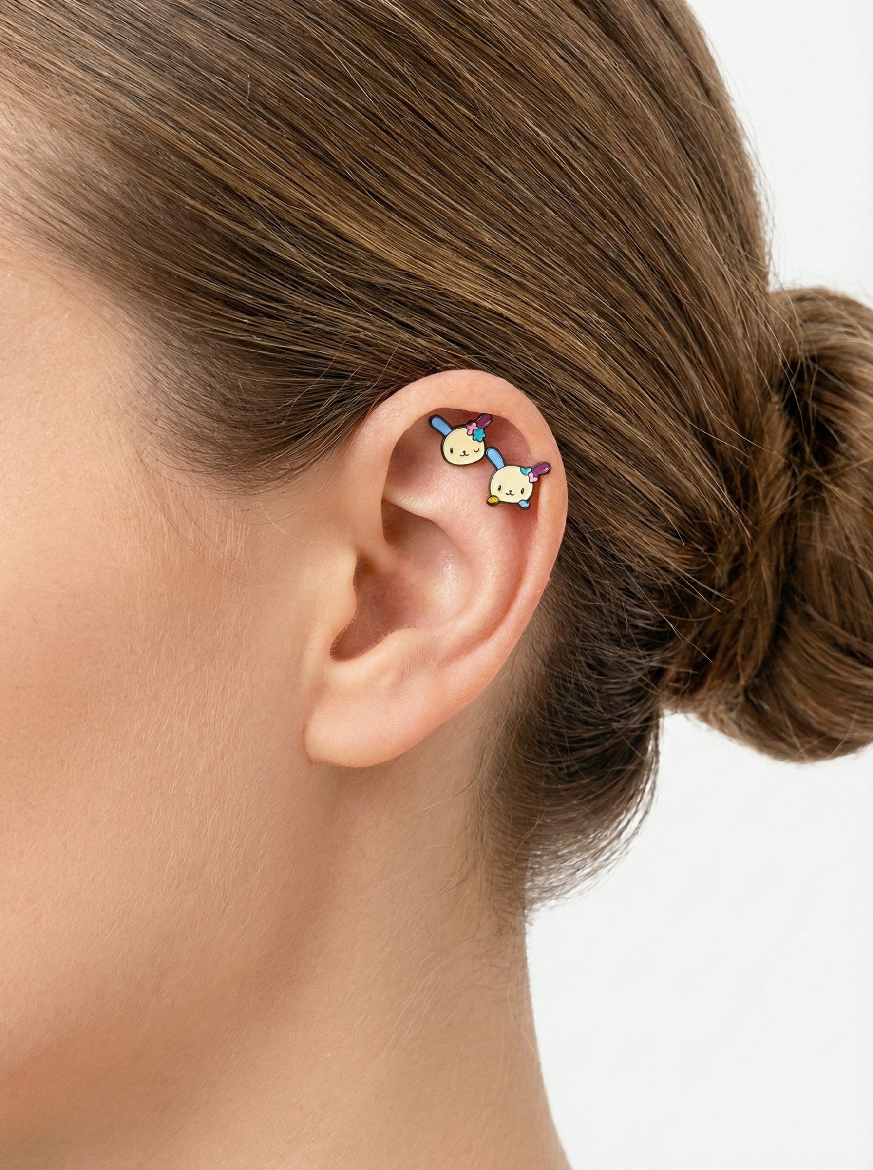 ear styling with two Ussahana-inspired pastel bunny-face barbell studs placed on the upper cartilage