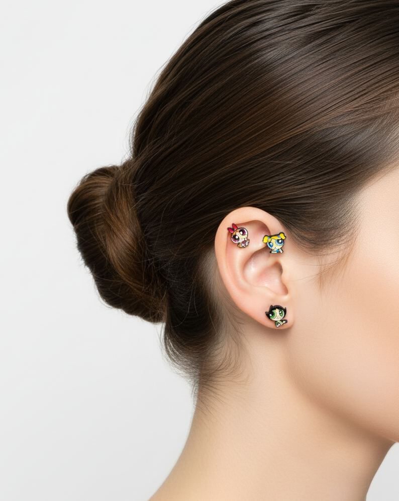 woman wearing three tiny Powerpuff Girls–inspired character barbell earrings stacked along the ear in a studio close-up.