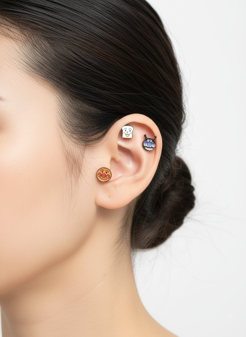 Close-up of a woman's ear wearing Anpanman character barbell earrings – featuring Anpanman, Baikinman, and Shokupanman studs on the helix and lobe.