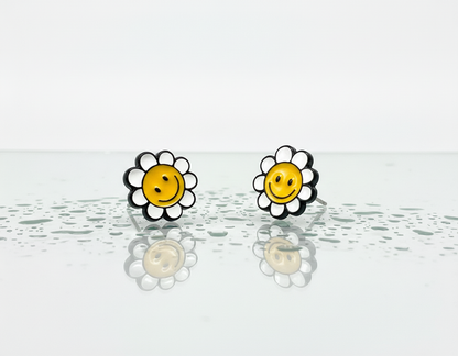 White smiley flower stud earrings with silver post, displayed on a reflective water-sprinkled surface.