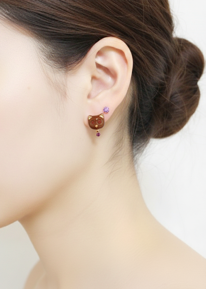 Model wearing brown enamel cat stud earrings with a purple crystal drop, styled with a lavender stud on the upper lobe