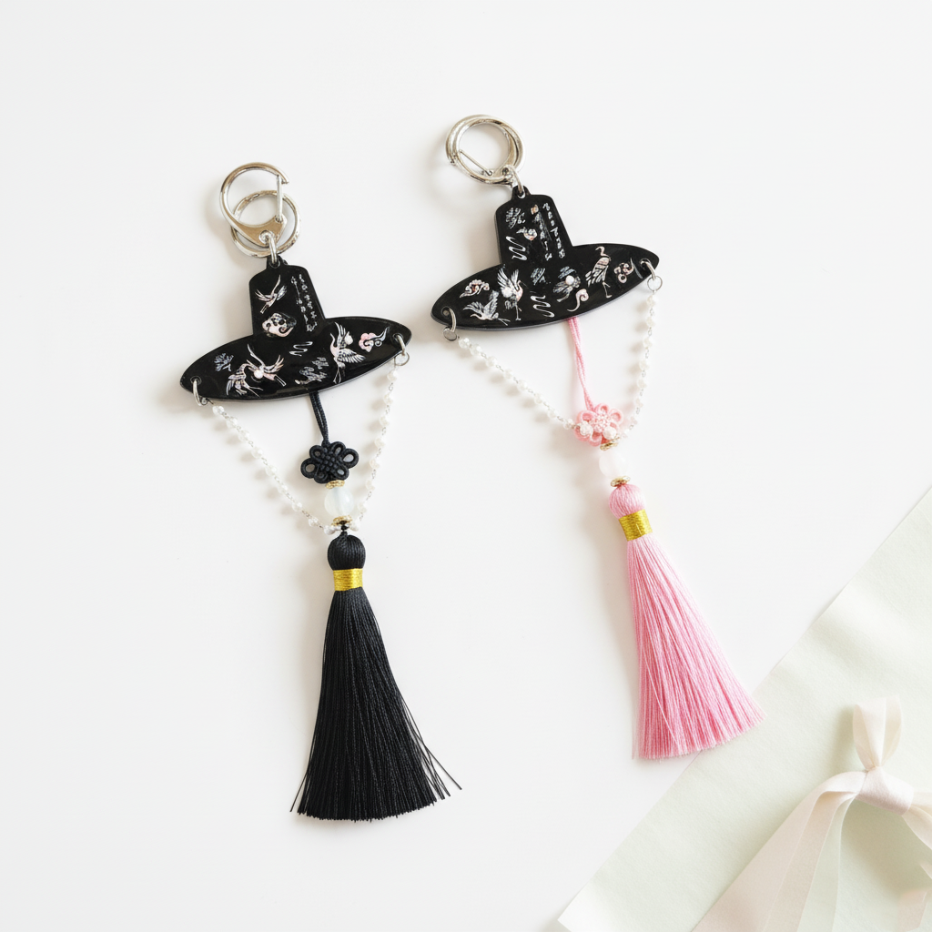 Both black and pink tassel keychains featuring traditional Korean gat and norigae details, displayed side by side with soft lighting.