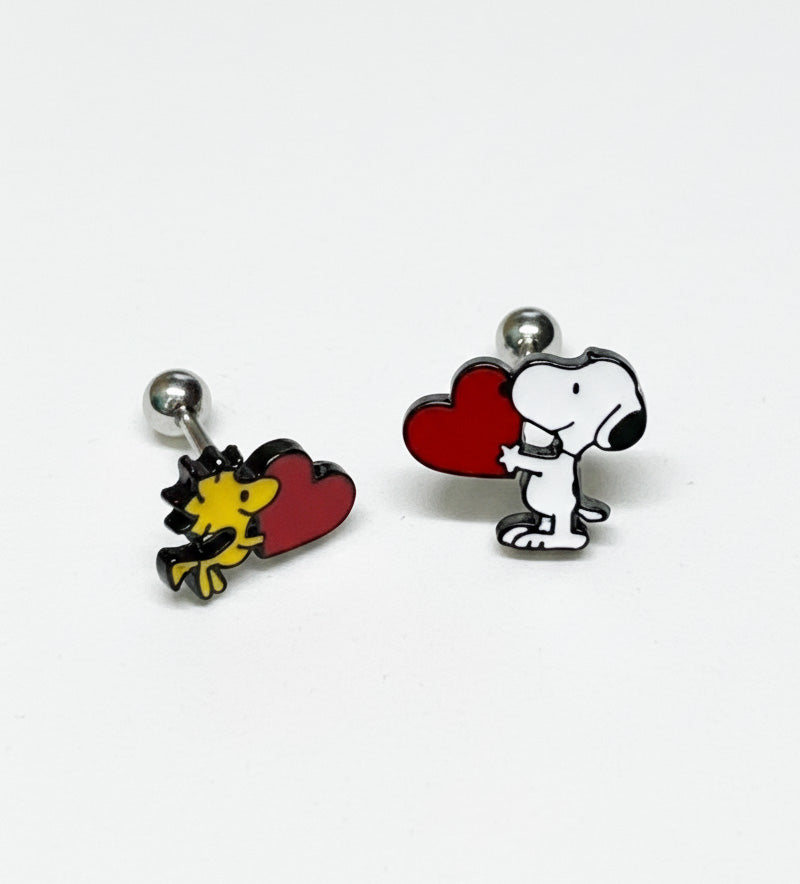 Product shot of Snoopy and Woodstock heart barbell earrings laid flat on white background.