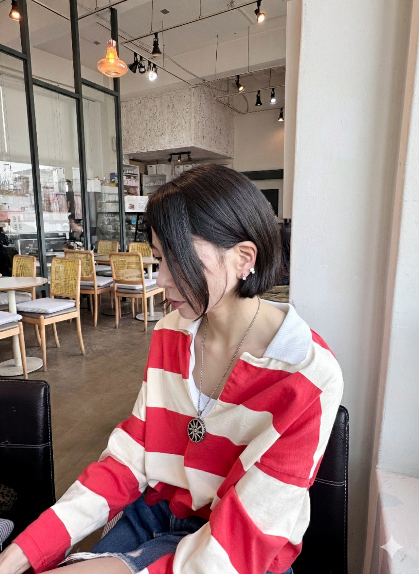 Woman wearing sun symbol pendant necklace with striped shirt