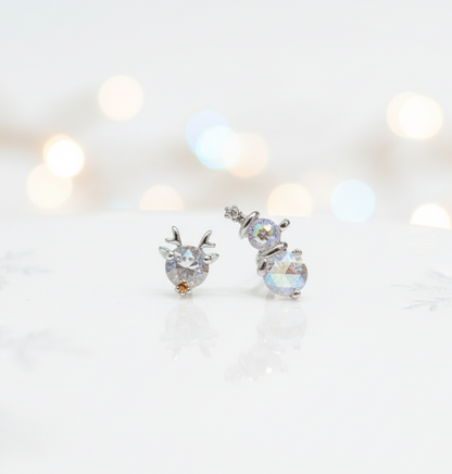 Aurora crystal snowman & reindeer barbell-ball earrings on frosty winter background — surgical steel Christmas jewelry product shot