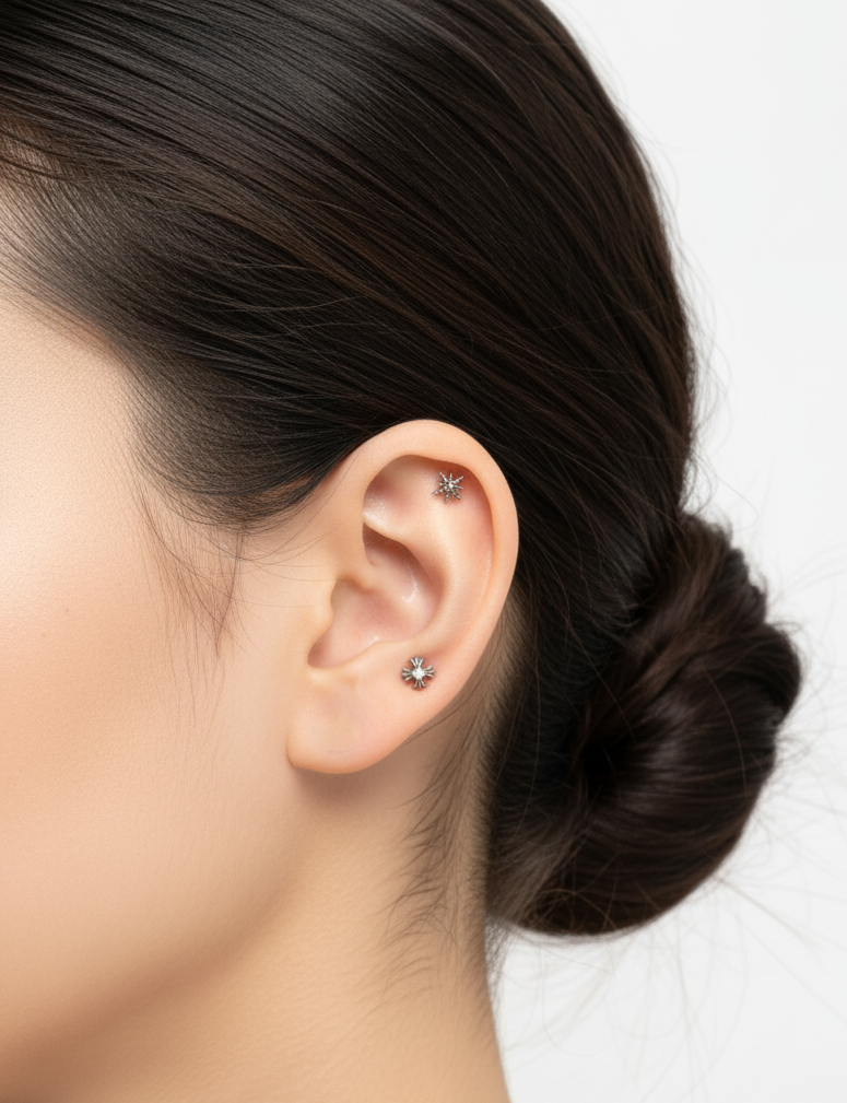 Minimal styling with two silver star piercings—upper helix and earlobe—against a clean white background. Neutral makeup and tidy updo enhance the elegant look.