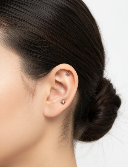 Minimal styling with two silver star piercings—upper helix and earlobe—against a clean white background. Neutral makeup and tidy updo enhance the elegant look.