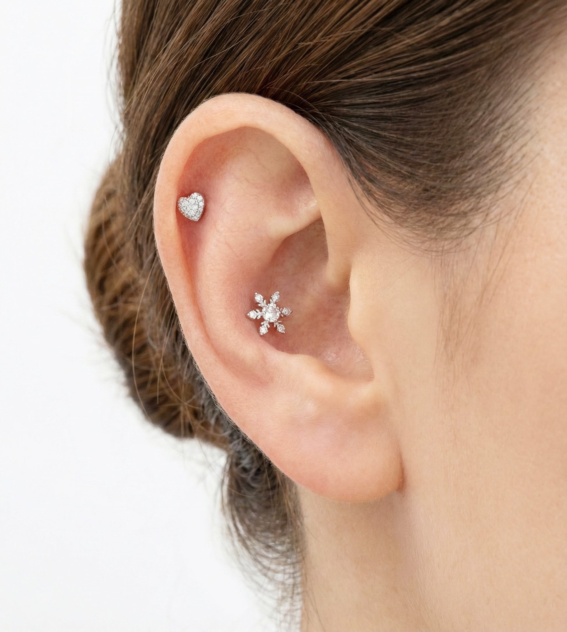 Silver pavé heart earring and snowflake stud styled together on the helix and inner conch.