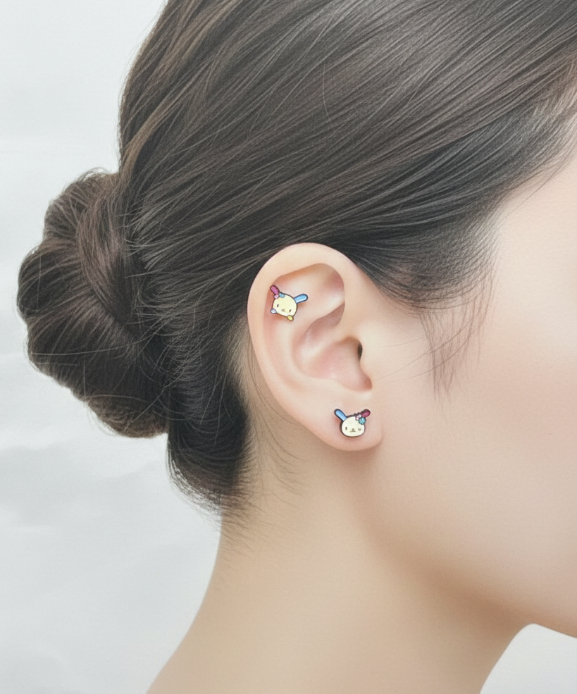 ear wearing two Ussahana-inspired pastel bunny-face barbell studs stacked on cartilage and lobe