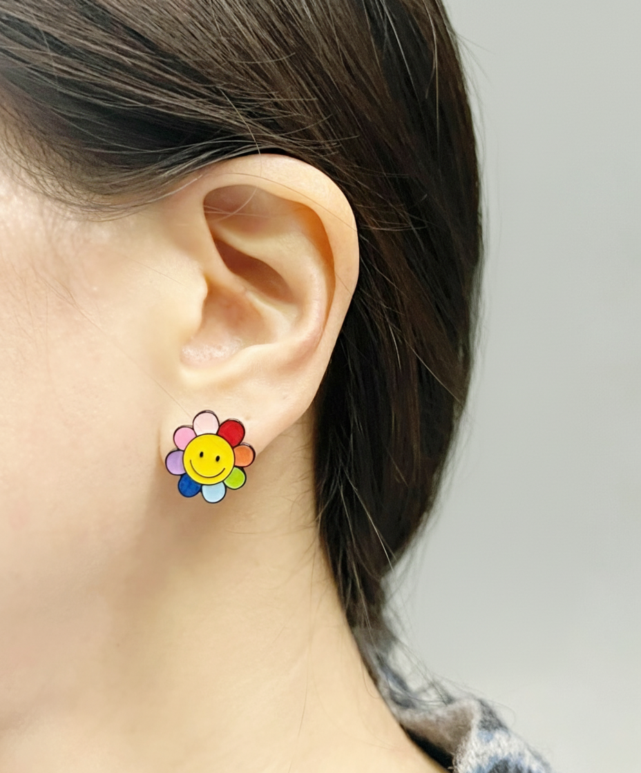 Colorful smiley flower earring with rainbow petals worn on the left earlobe, styled with dark hair pulled back