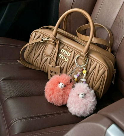 Miu Miu handbag with fluffy keychains on a car seat