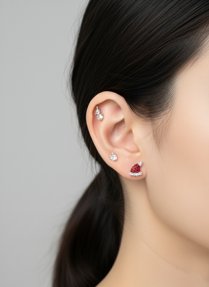 Ear stacking close-up — helix snowman, lobe Santa hat stud and mini reindeer stud layered on mode