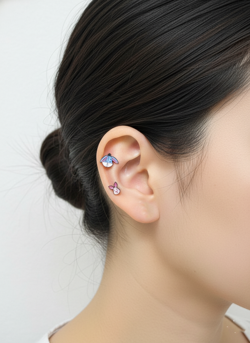 Piglet and Eeyore enamel earrings styled vertically on a single ear, showing playful layering.