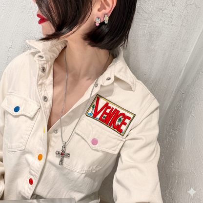 Gothic cross necklace with red gem worn with white shirt