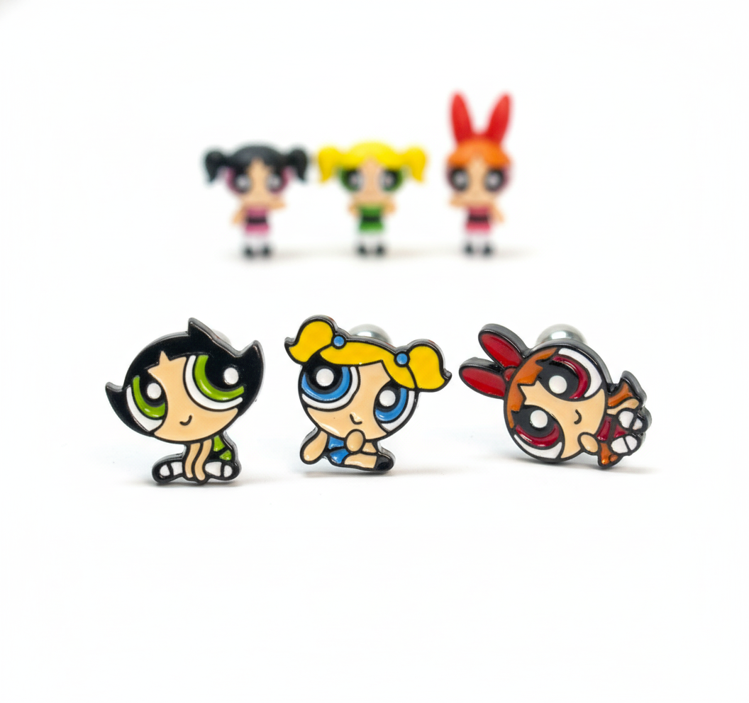 three Powerpuff Girls–inspired character barbell earrings posed in the front with matching figures softly blurred behind them