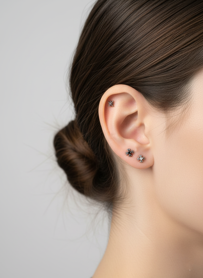Ear stack featuring three barbells with radiant designs—sunburst, starburst, and mystic dot. Natural light highlights the textured silver finish.