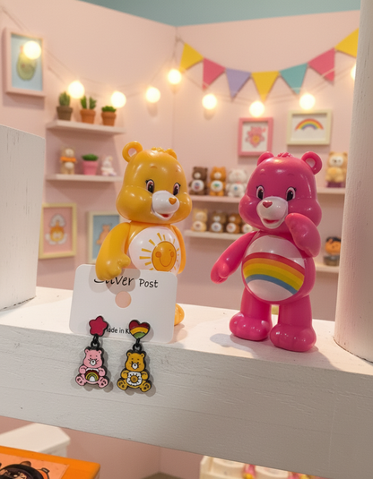 Close-up of pink and yellow bear earrings placed on a white wooden shelf, surrounded by retro bear figurines and warm string lights in a pastel-themed room.